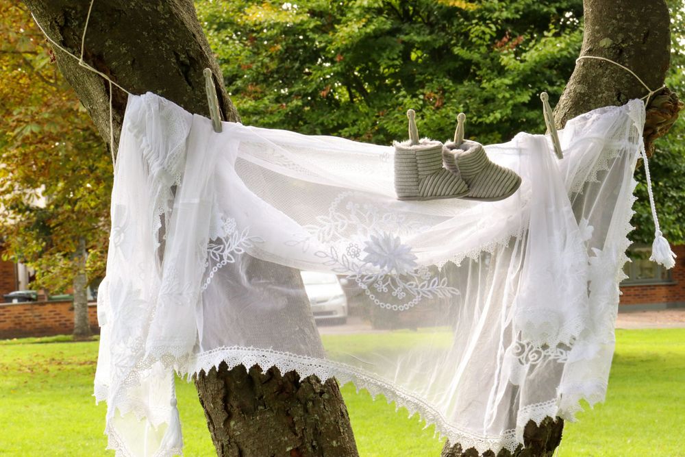White lace fabric draped between trees creating an ethereal outdoor display.