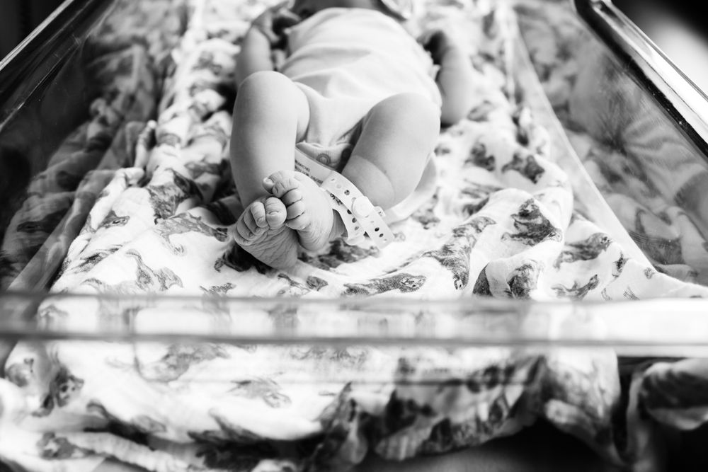 Black and white image of newborn baby girl in her bassinet focused on her feet.