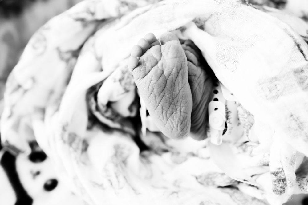Black and white image of newborn baby girl with wrinkly feet.