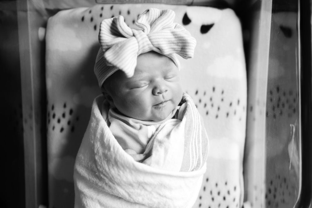 Black and white image of newborn baby girl swaddled in bassinet.  Location is Piedmont Hospital in Augusta, GA.