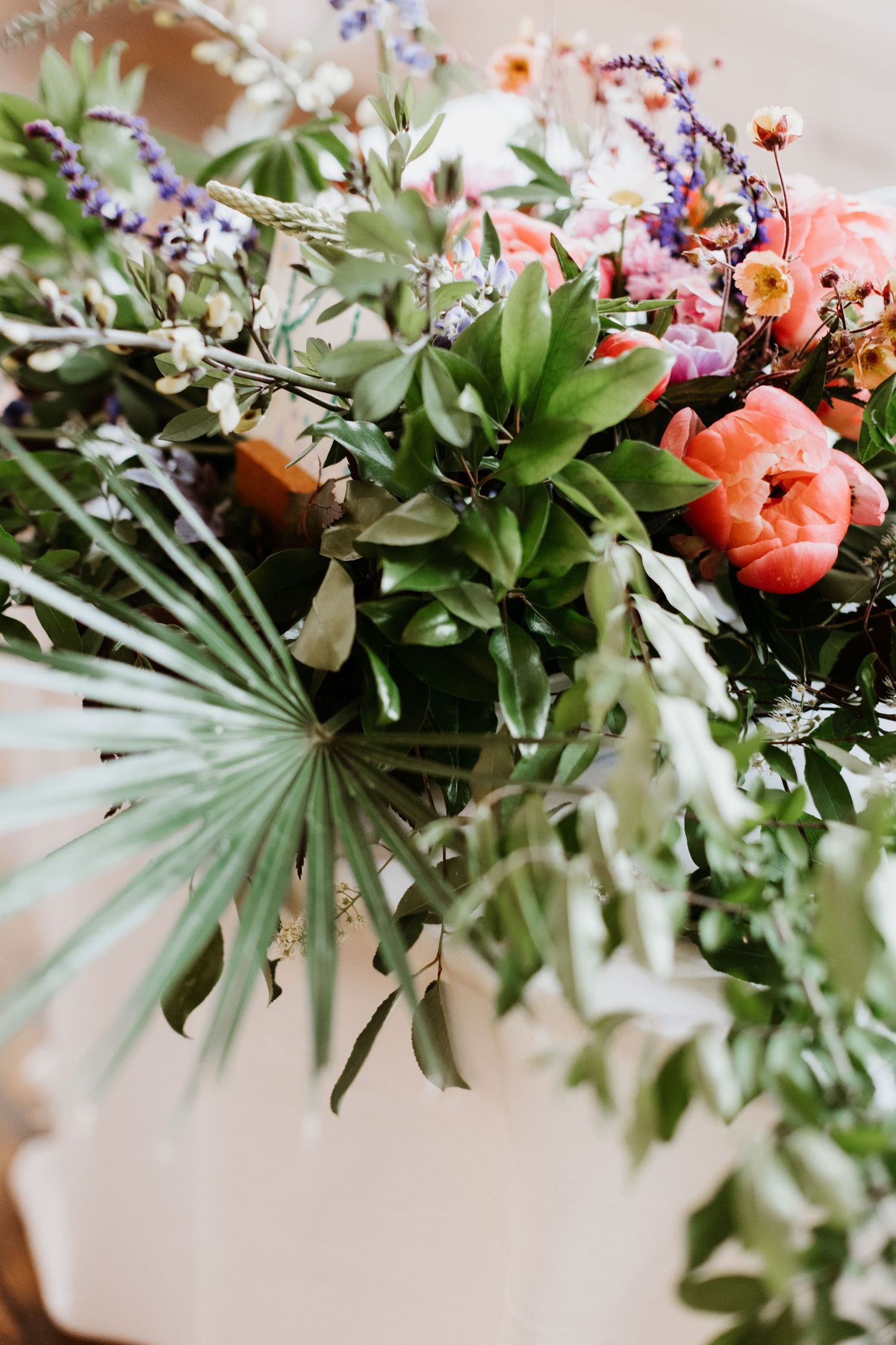 Lush wedding floral arrangement featuring coral peonies, lavender, and tropical palm leaves. New Bedford, Ma. Miranda Photo & Co