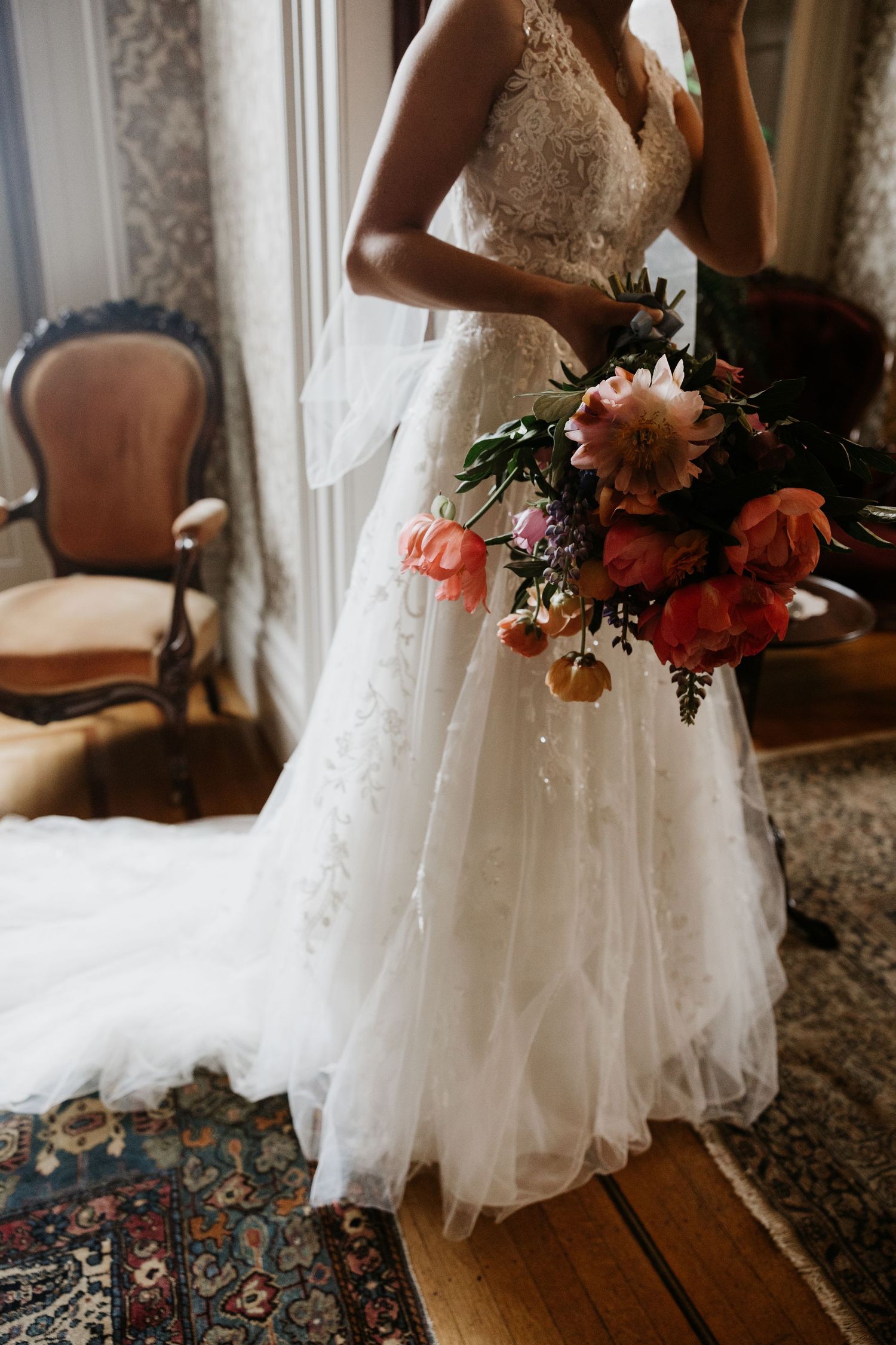 Bride in lace wedding gown holds vibrant coral and pink bridal bouquet in vintage room. New Bedford, Ma. Miranda Photo & Co