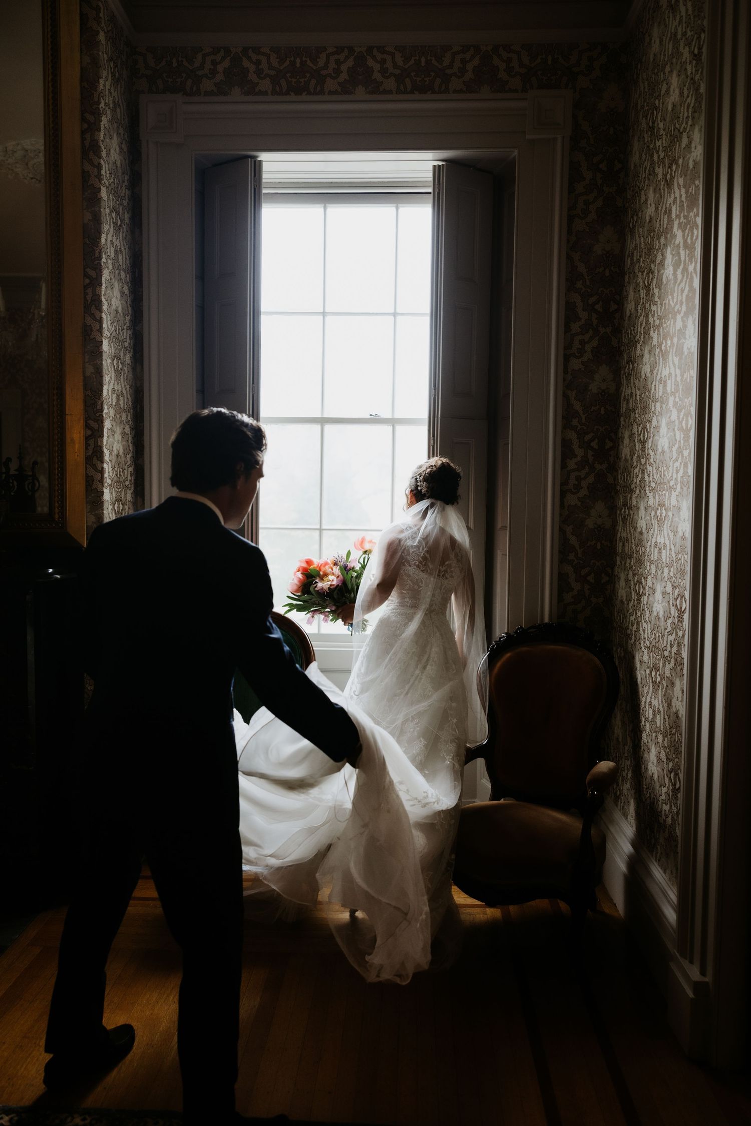 Silhouette of bride and groom sharing a romantic moment by a bright window in an elegant vintage room. New Bedford, Ma. Miranda Photo & Co