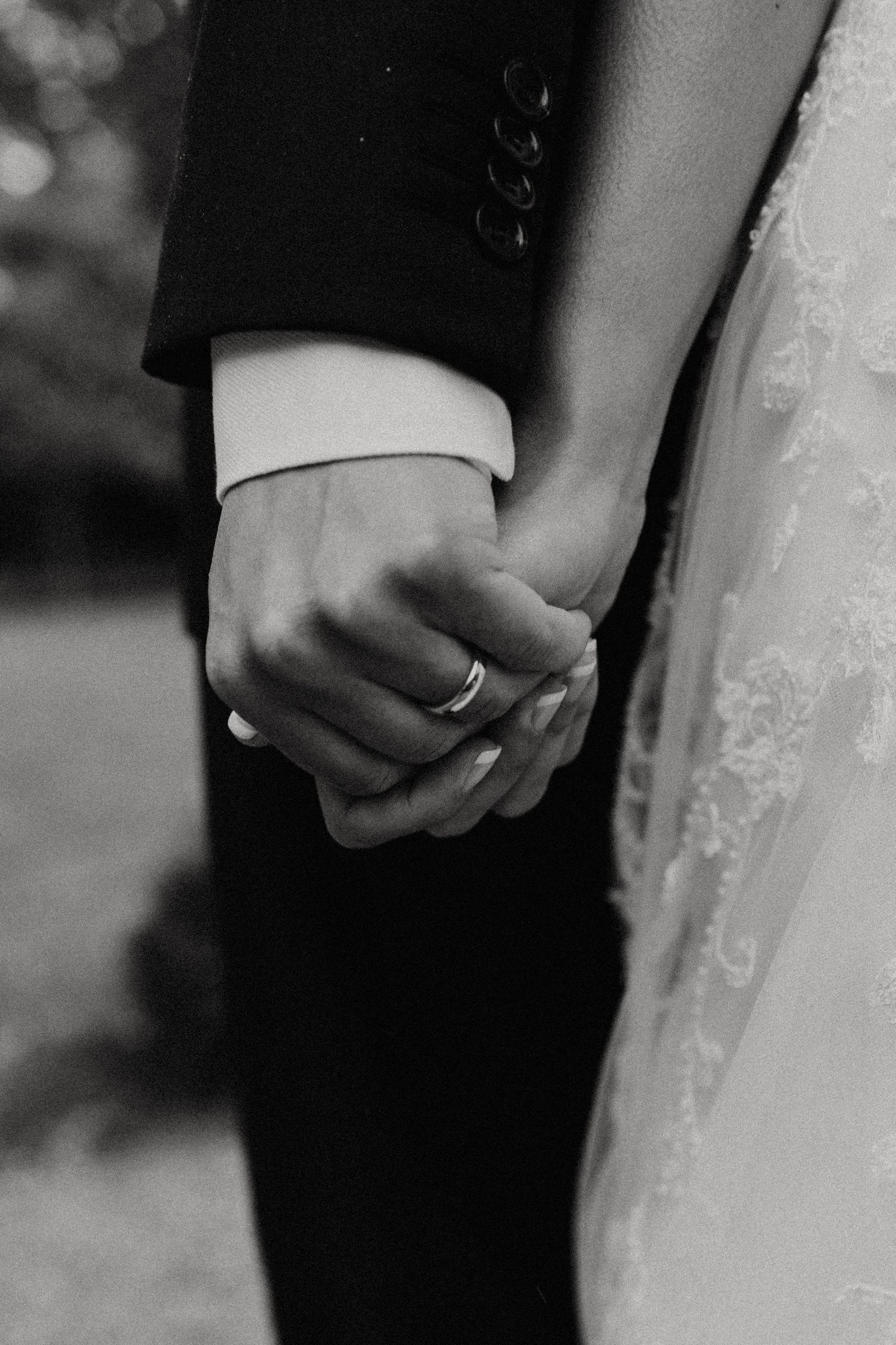 Black and white close-up of bride and groom holding hands, showing wedding rings, in formal attire.New Bedford, Ma. Miranda Photo & Co