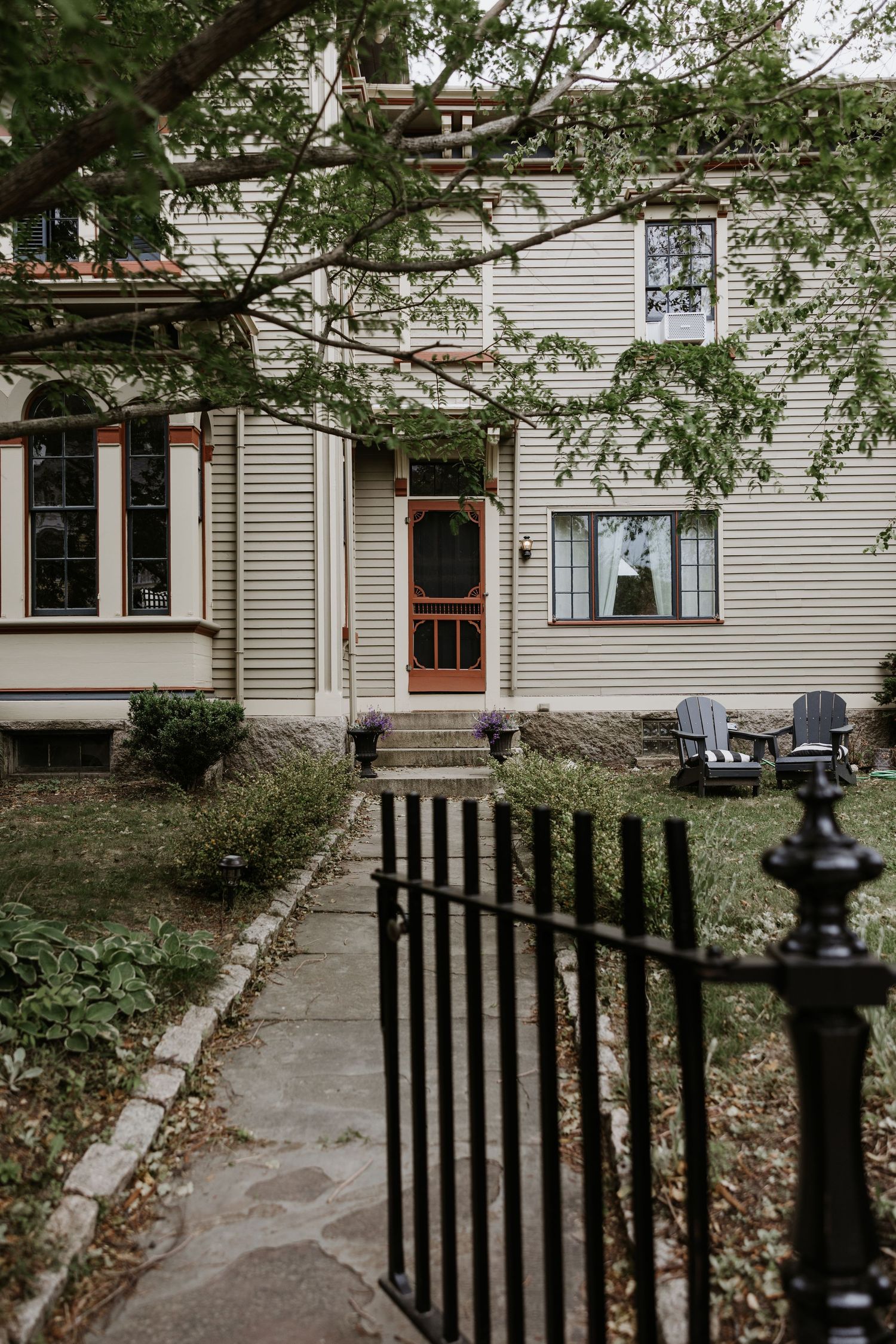 Charming white colonial wedding venue exterior with black iron fence and lush green trees. New Bedford, Ma. Miranda Photo & Co