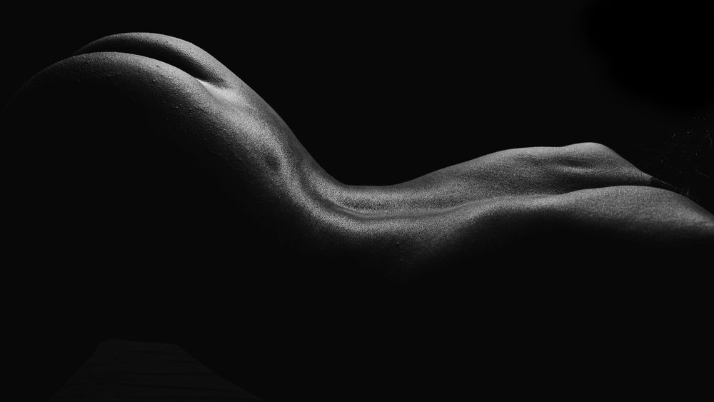 Abstract bodyscape photograph emphasizing flowing lines and shadows.