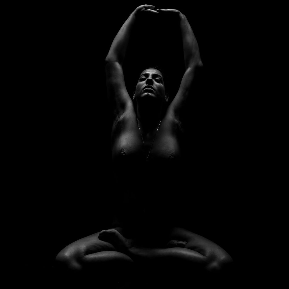 Dramatic black and white portrait with upraised arms creating elegant lines and shadows.