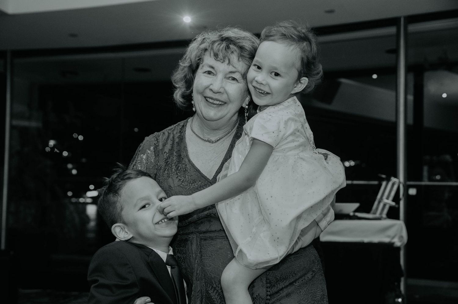 Family shares joyful moment during black and white wedding reception portrait.