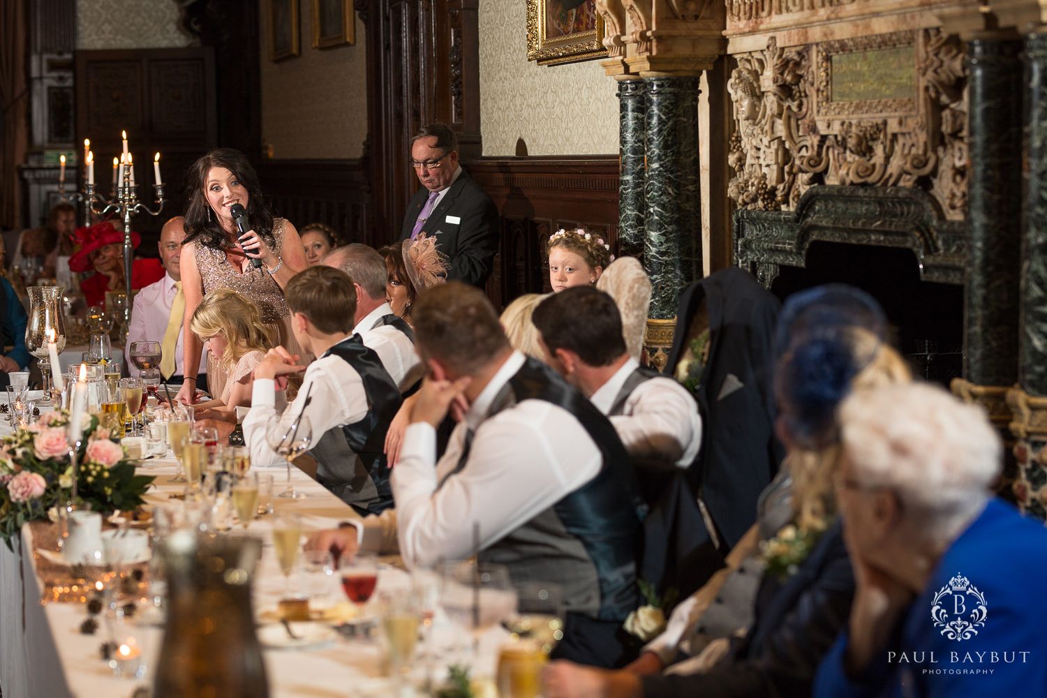 Wedding reception dinner in an elegant historic room with ornate decor and candlelight.