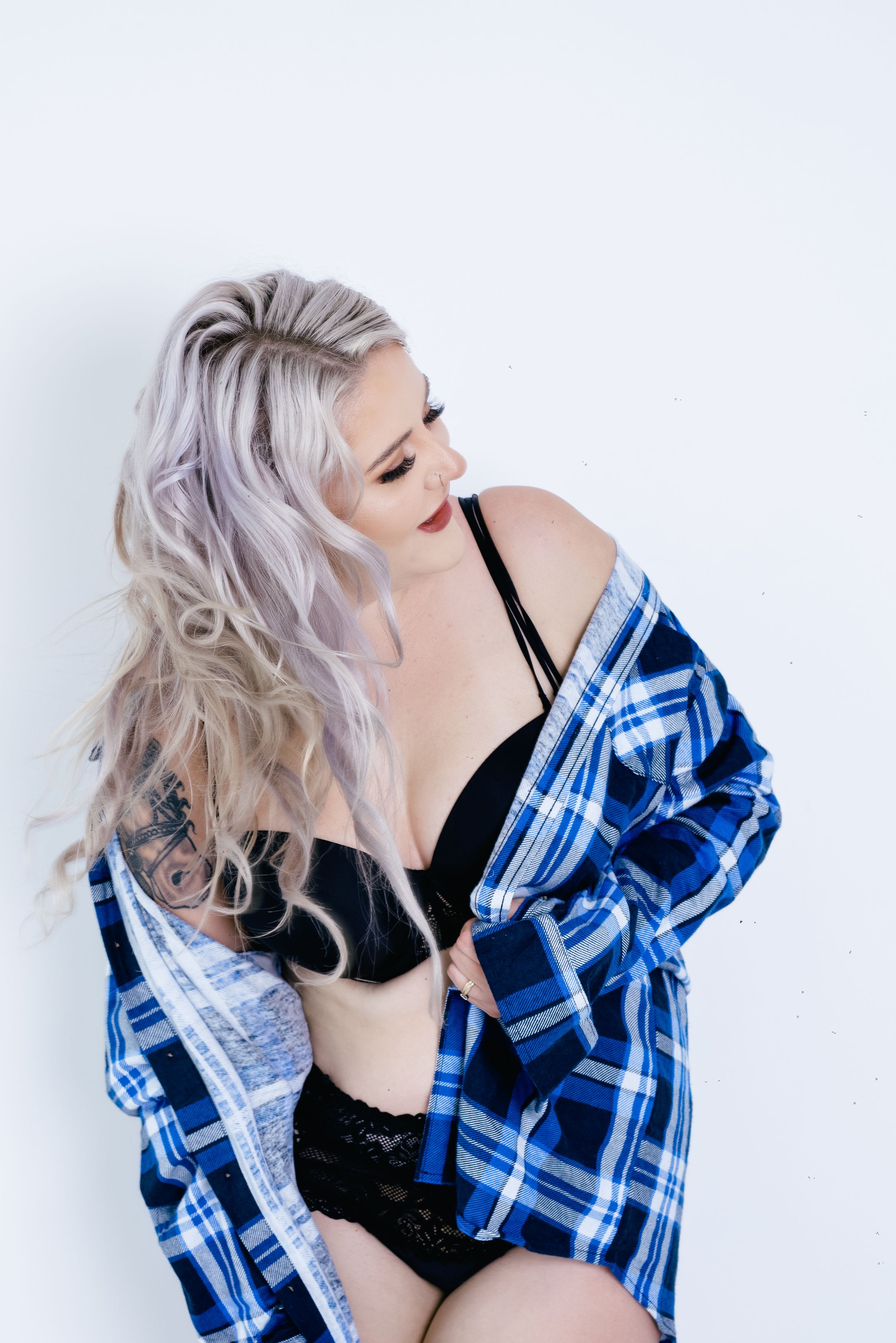 Boudoir photo featuring soft lighting with a blue plaid flannel worn over black lingerie.