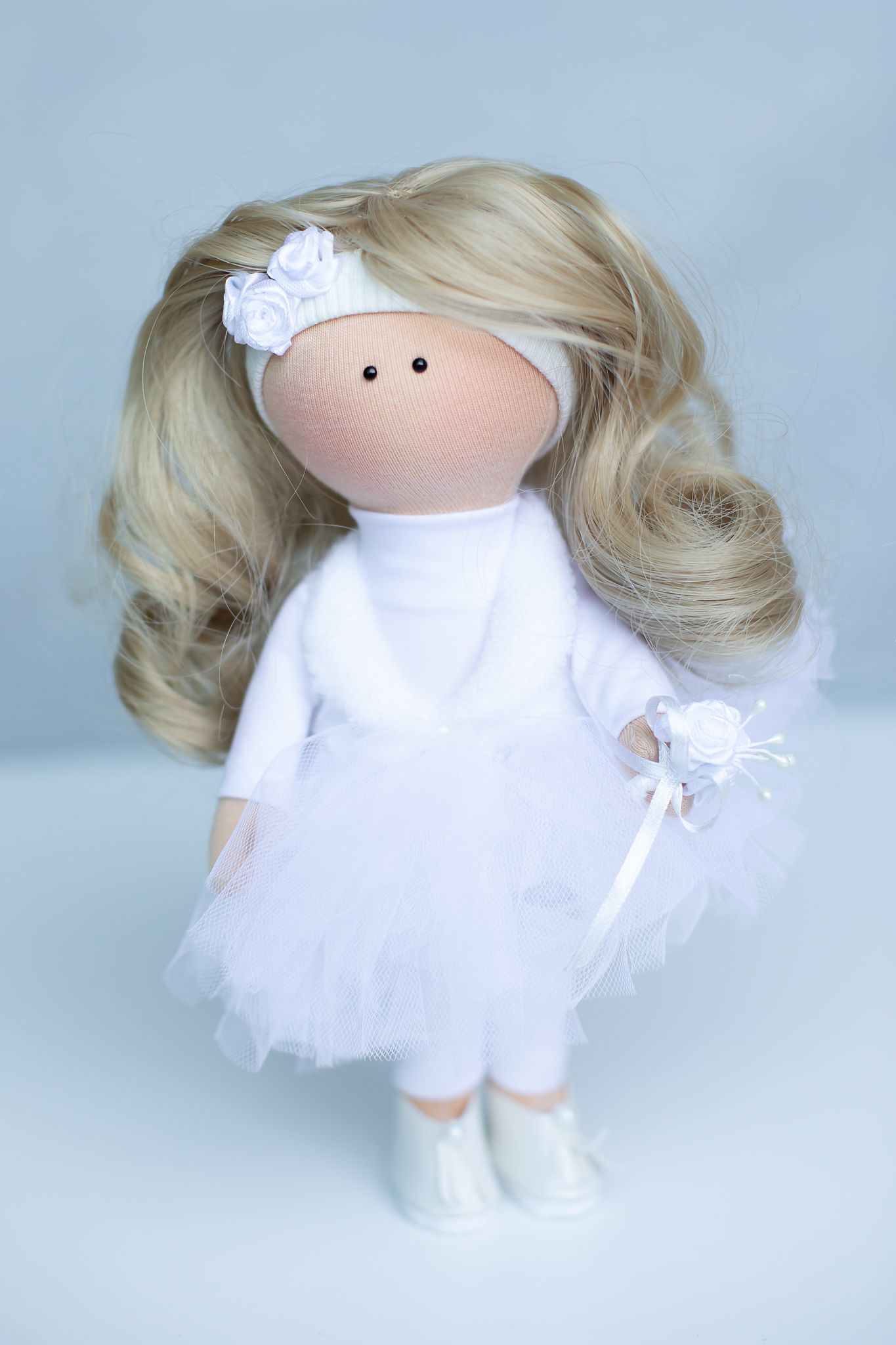 Handmade blonde fabric doll wearing a white tutu skirt and floral headband holding a small wand.
