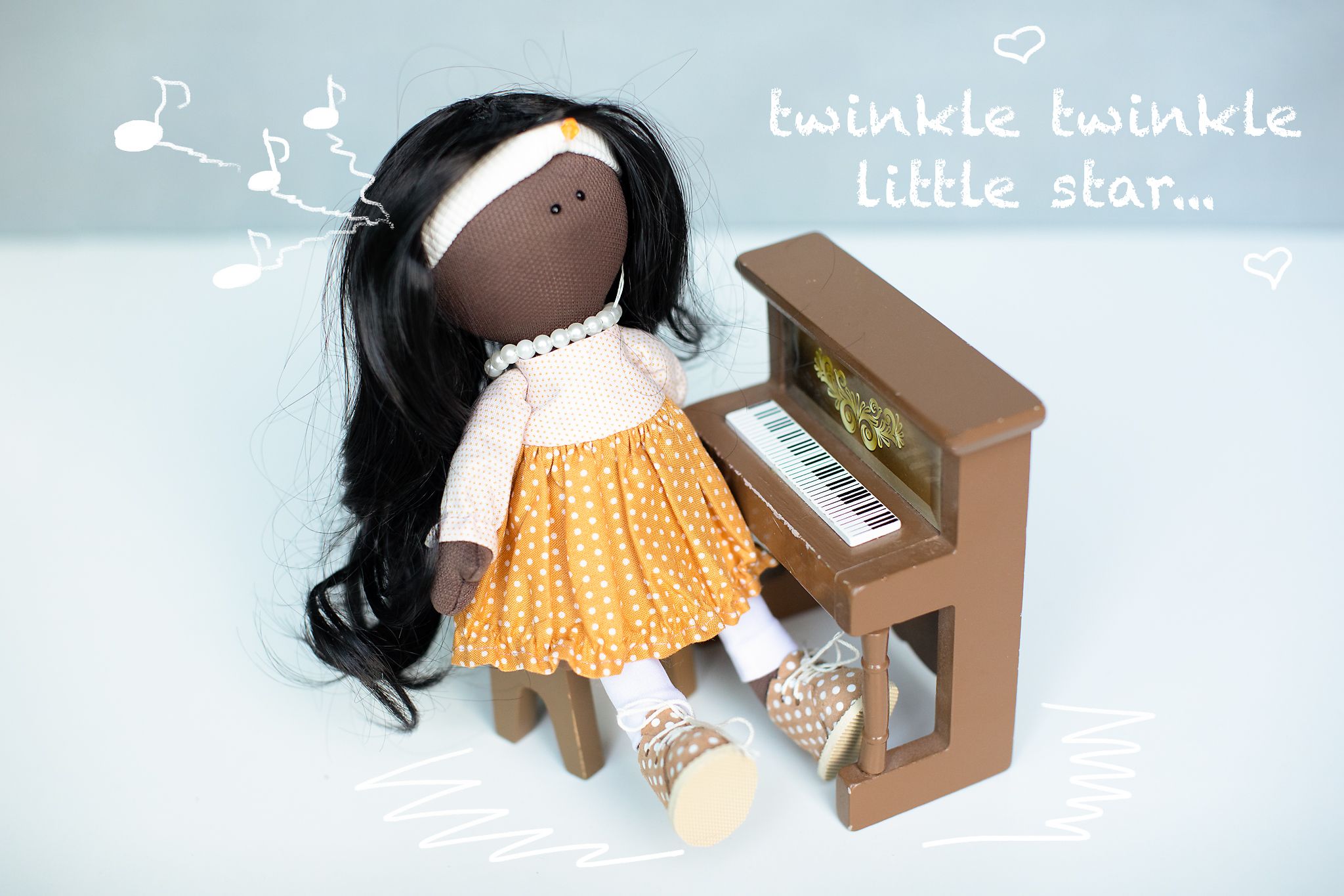 Handmade dark-haired fabric doll at a miniature piano with twinkle twinkle little star text overlay.