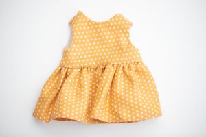 Yellow polka dot sleeveless doll dress with gathered skirt on a white background.