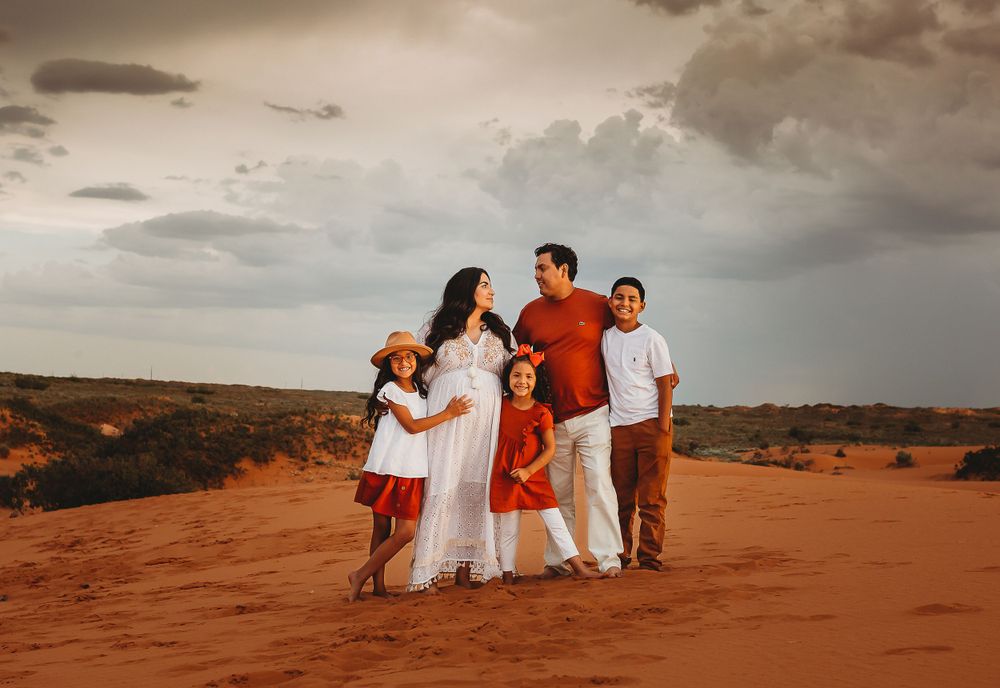 family in the sand dunes hugging dressed in boho
