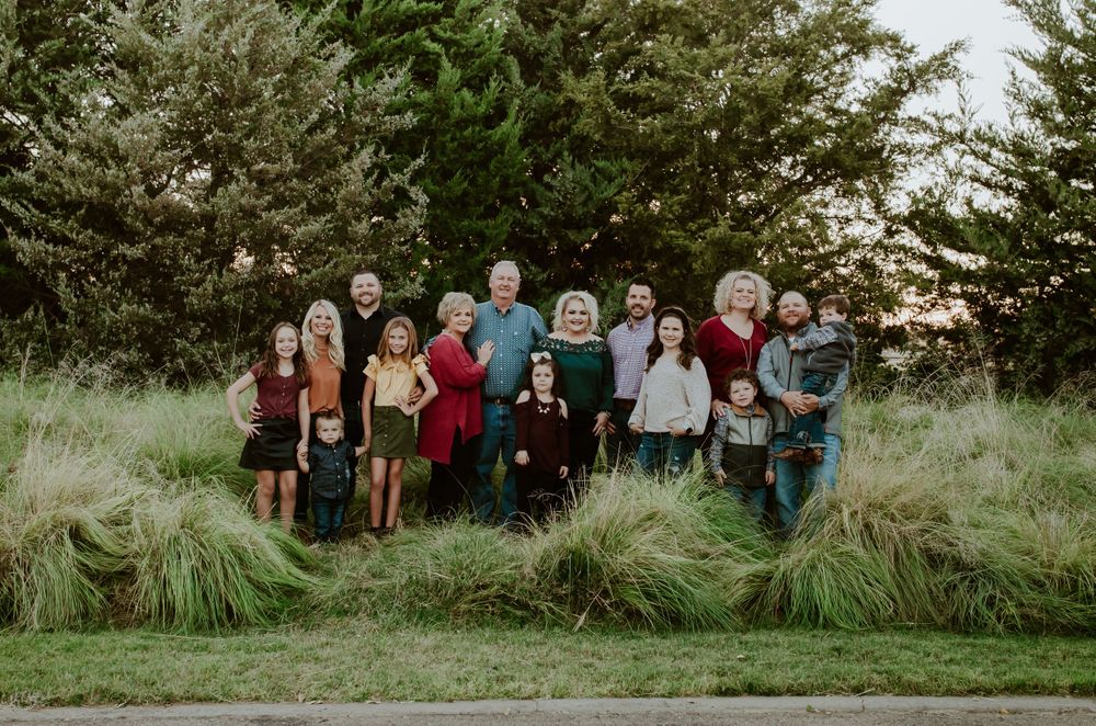 large family dressed in colorful outfits arrangement by sibling groups at the park infant of beautiful trees