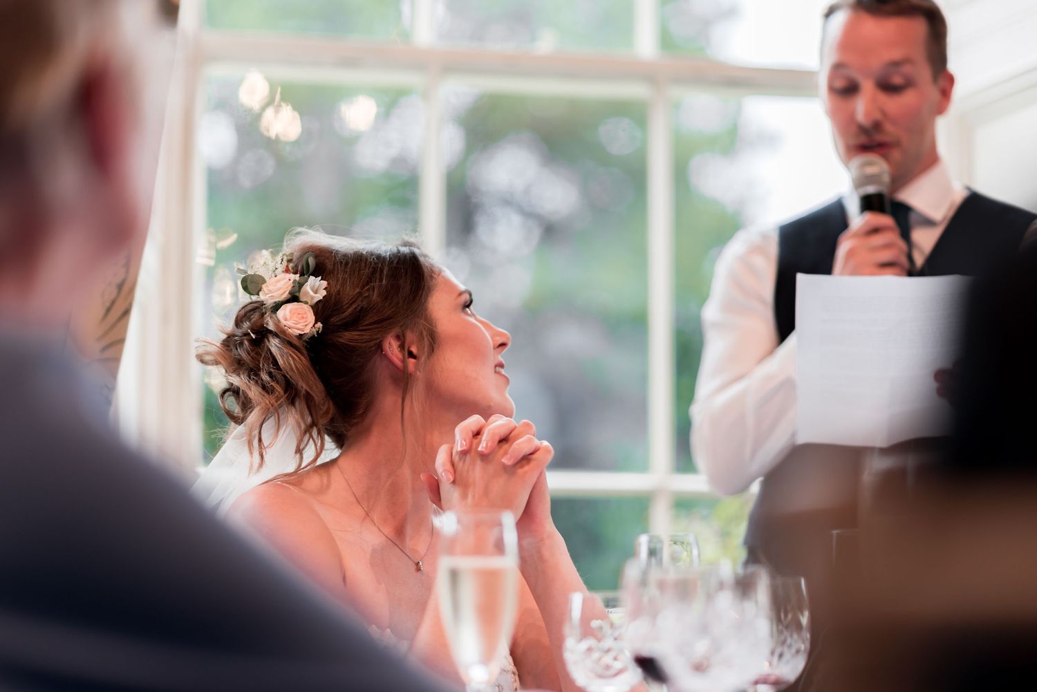 An emotional moment captured during wedding reception speeches with guests listening intently.