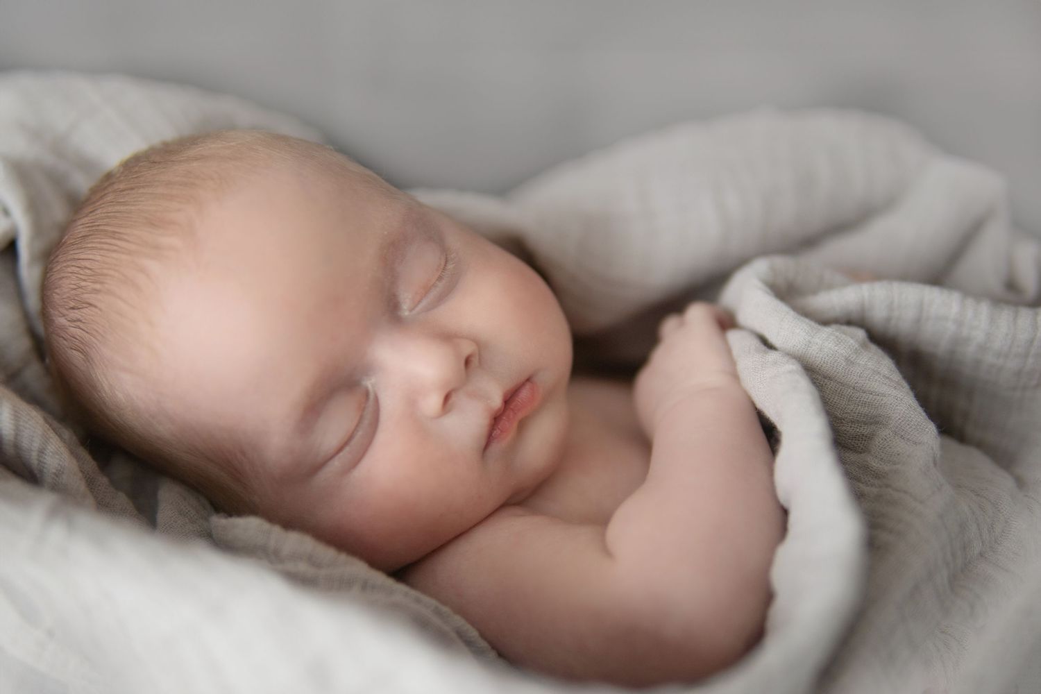 Peacefully sleeping newborn cuddled in a soft blue blanket