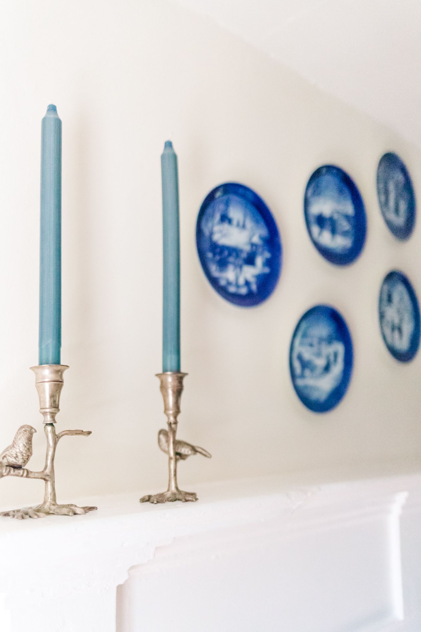 Blue candles on a white mantle with blue plates hanging on the wall. Brand photos Watergrasshill B+ B, Hudson Valley, NY