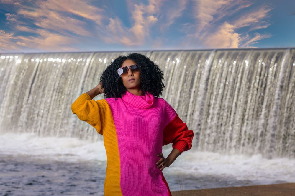 A vibrant outfit combination photographed against a flowing waterfall backdrop.
