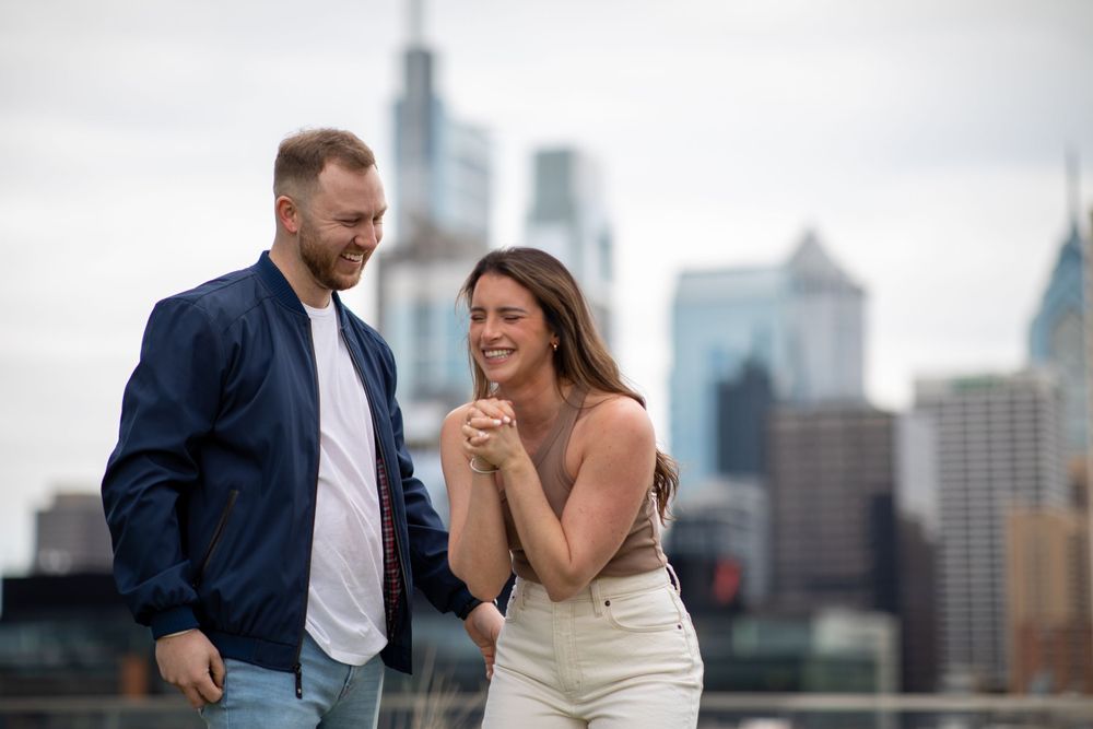 Joyfully celebrating their engagement with city skyline as backdrop.