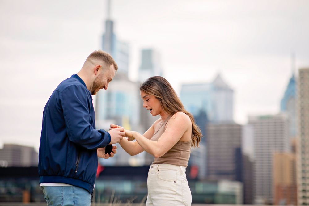 Happy couple during engagement with downtown skyline in background.