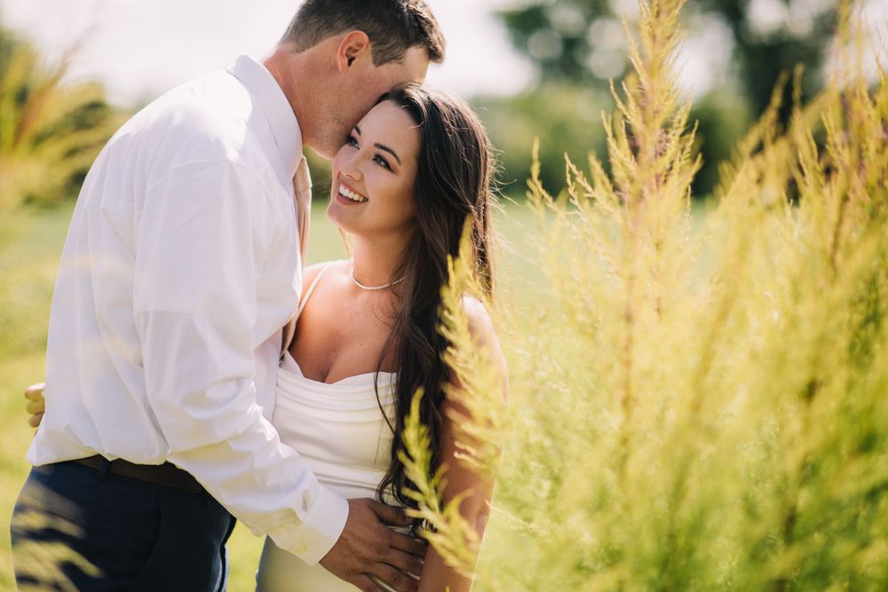 A romantic moment between a couple standing in golden wheat field at sunset.