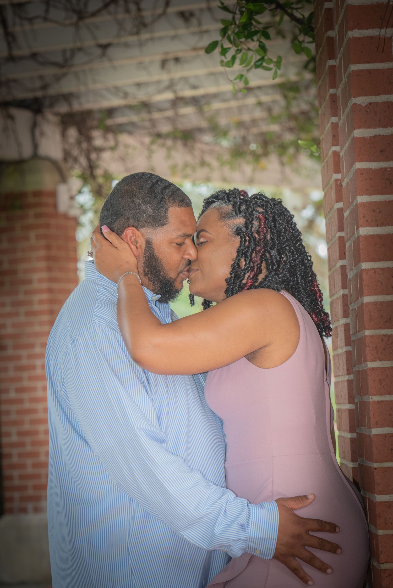 Intimate couple's portrait showing tender moment between brick columns.