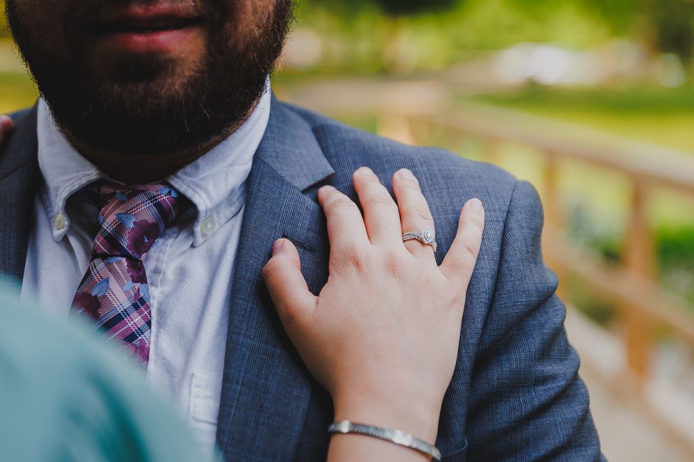 Close-up detail of hands resting on formal attire during an engagement photo session.