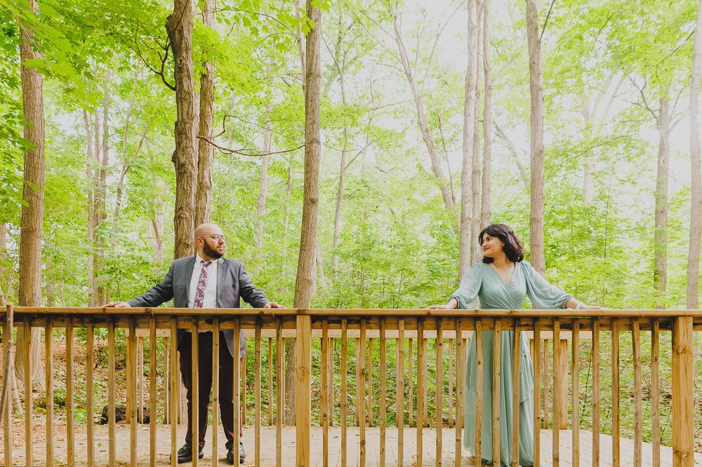 A playful embrace captured in a wooded setting with bright spring foliage.