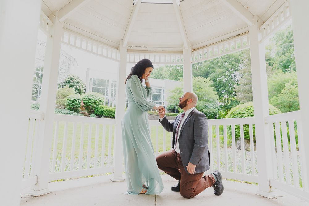 A couple sitting back-to-back in a white gazebo during an intimate moment.