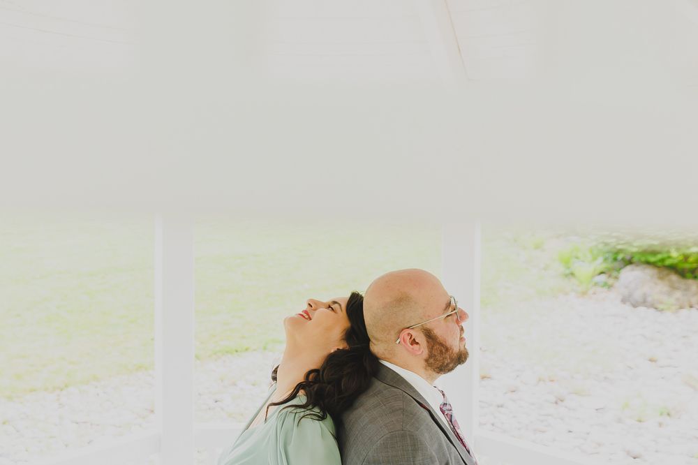 A romantic portrait of a couple in formal wear inside a white gazebo.