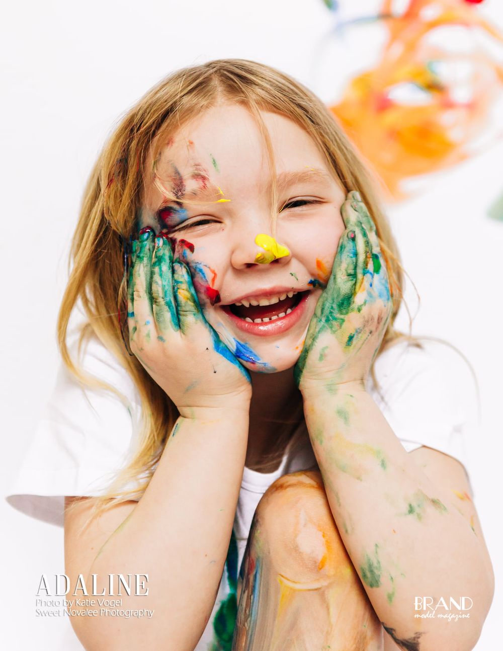 Joyful portrait with paint-covered hands and colorful artistic expression.