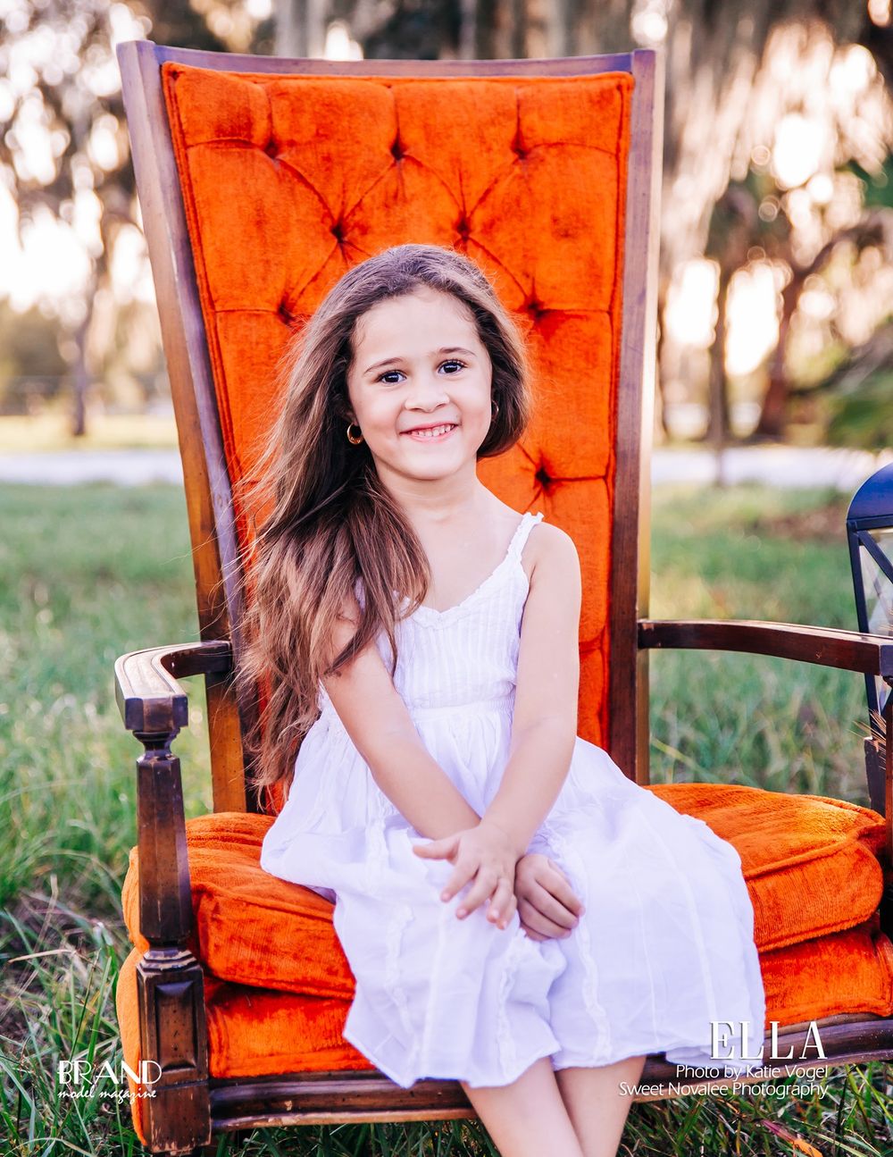 Classic portrait on vintage orange tufted chair in natural outdoor setting.