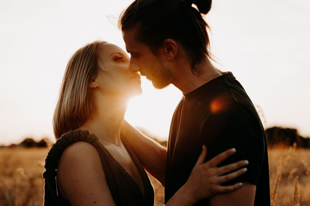Romantic sunset silhouette of couple embracing in golden field.