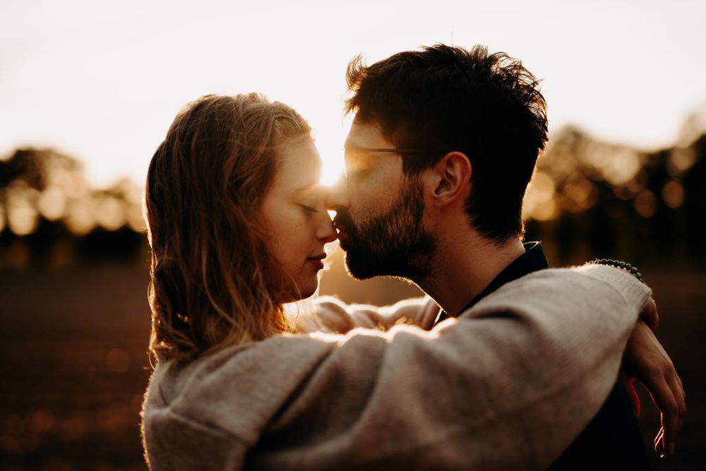 Intimate close-up portrait of couple sharing tender moment in warm sunlight.