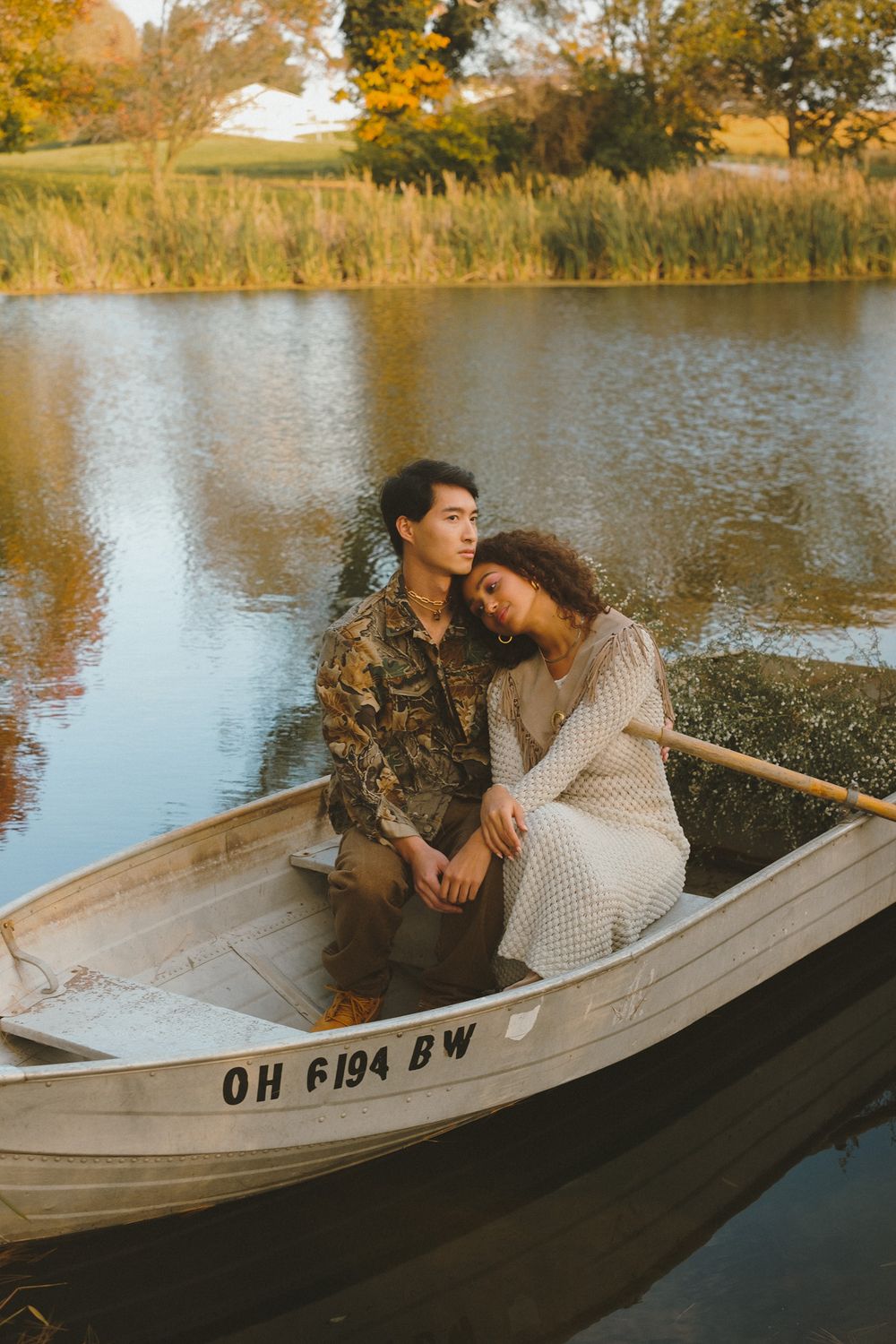 Romantic autumn boat ride on calm lake with fall foliage in background.