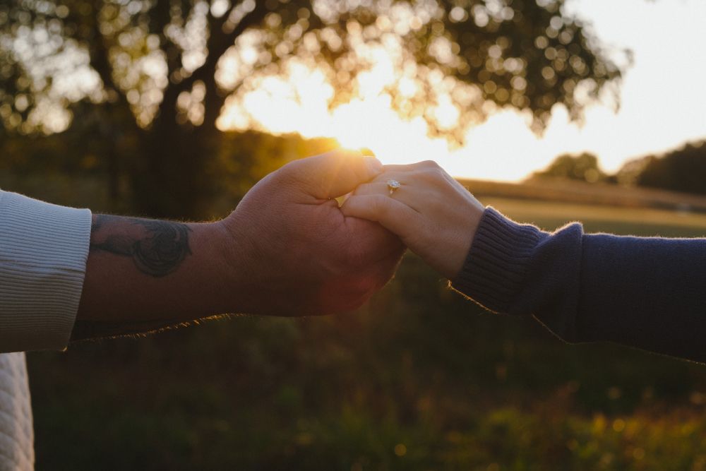 Hands reach out to connect during a romantic sunset moment.