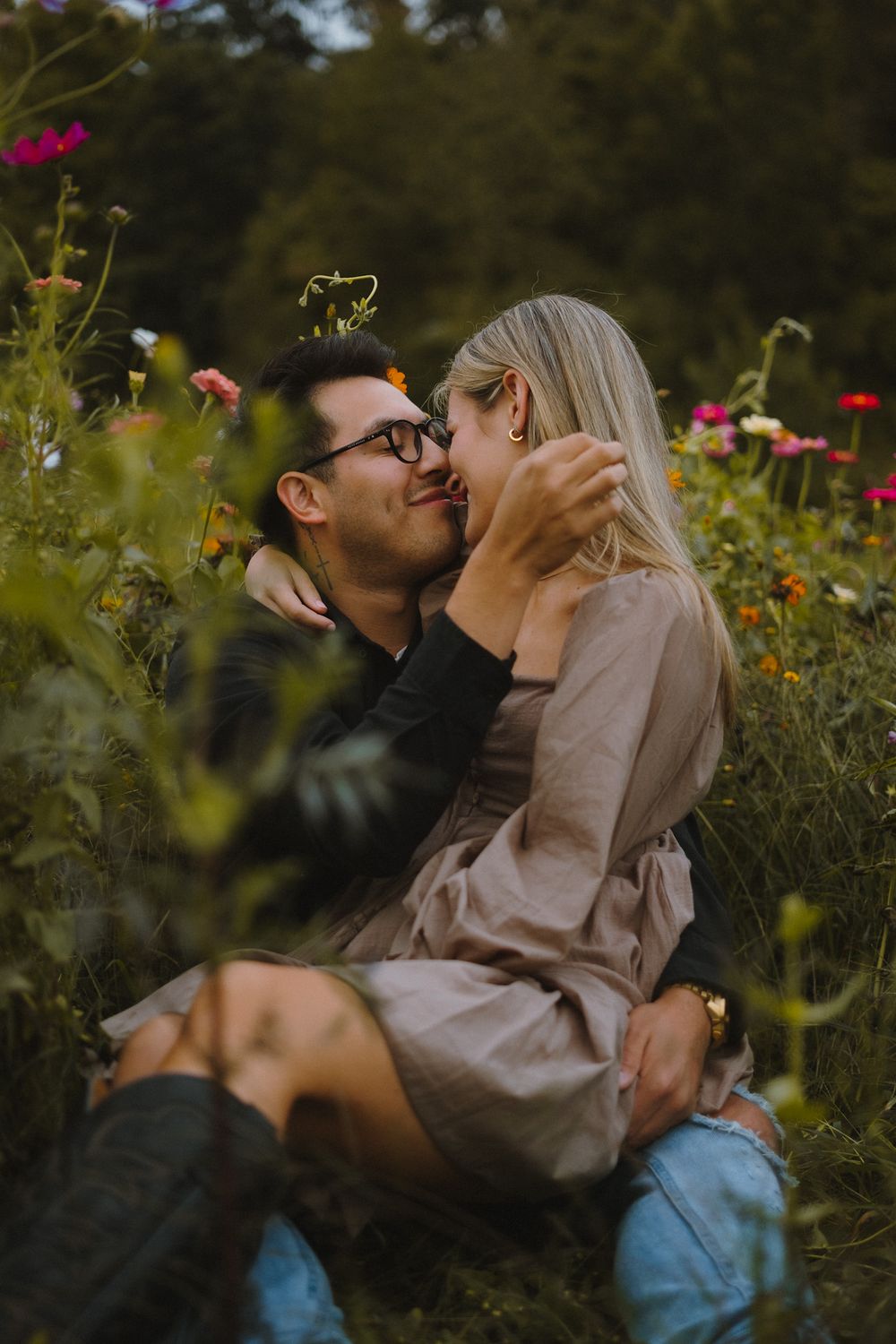 A romantic couple shares tender moments among wildflowers in a garden setting.