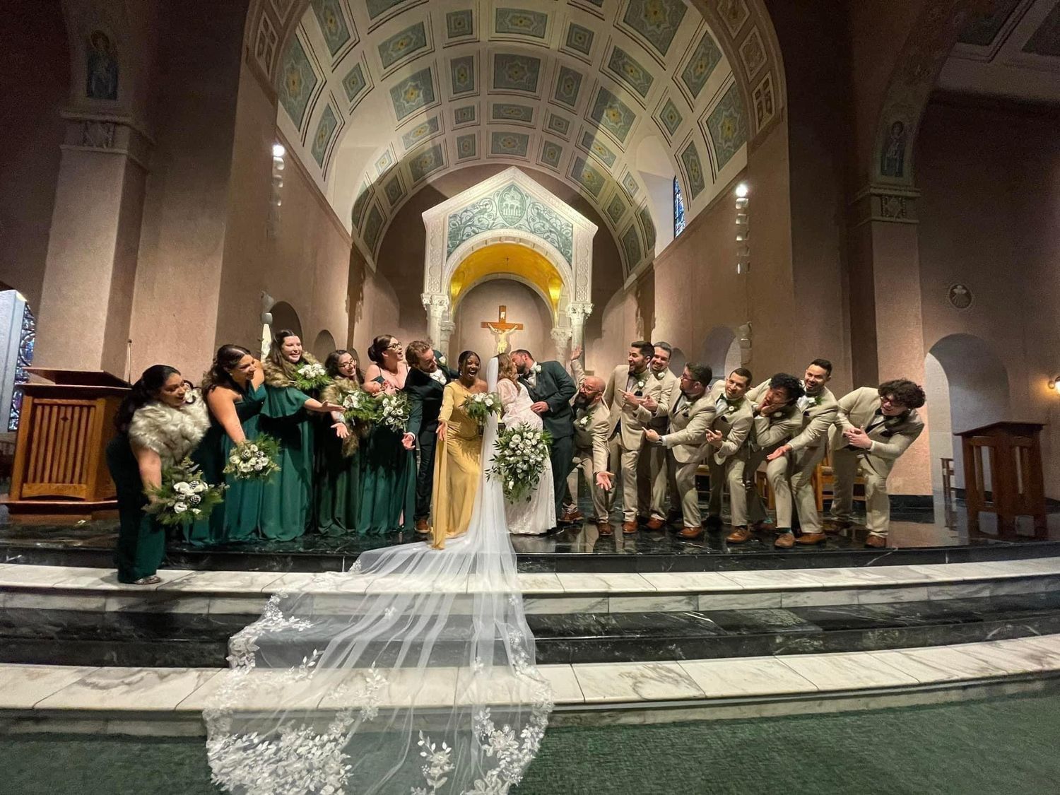 a large wedding party all face and lean in towards the bride and groom who are in the middle