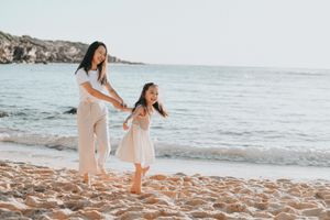 A mother and daughter enjoy a playful walk along a rocky beach, sharing a joyful dance with sunrise of little bay