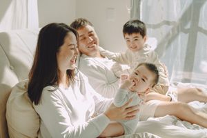Intimate and cozy newborn photography session at home,  a family snuggled up on bed, bathed in natural light