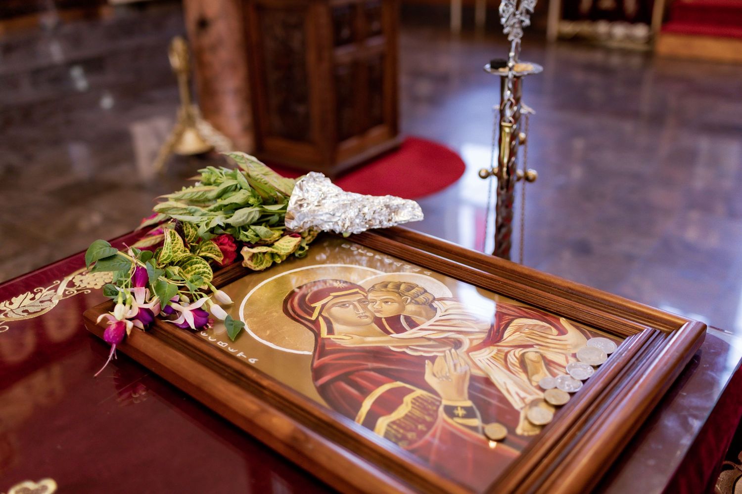 Religious icon displayed on red cloth with decorative elements in church setting.