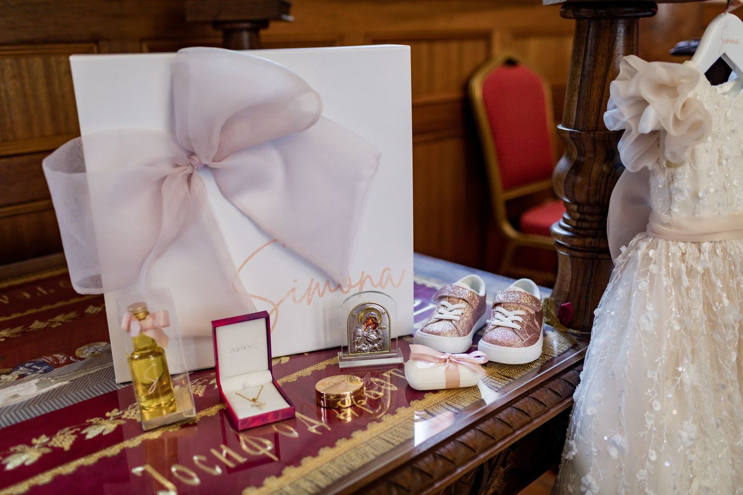 Baptism gifts and decorations displayed including baby shoes, dress, and wrapped presents.