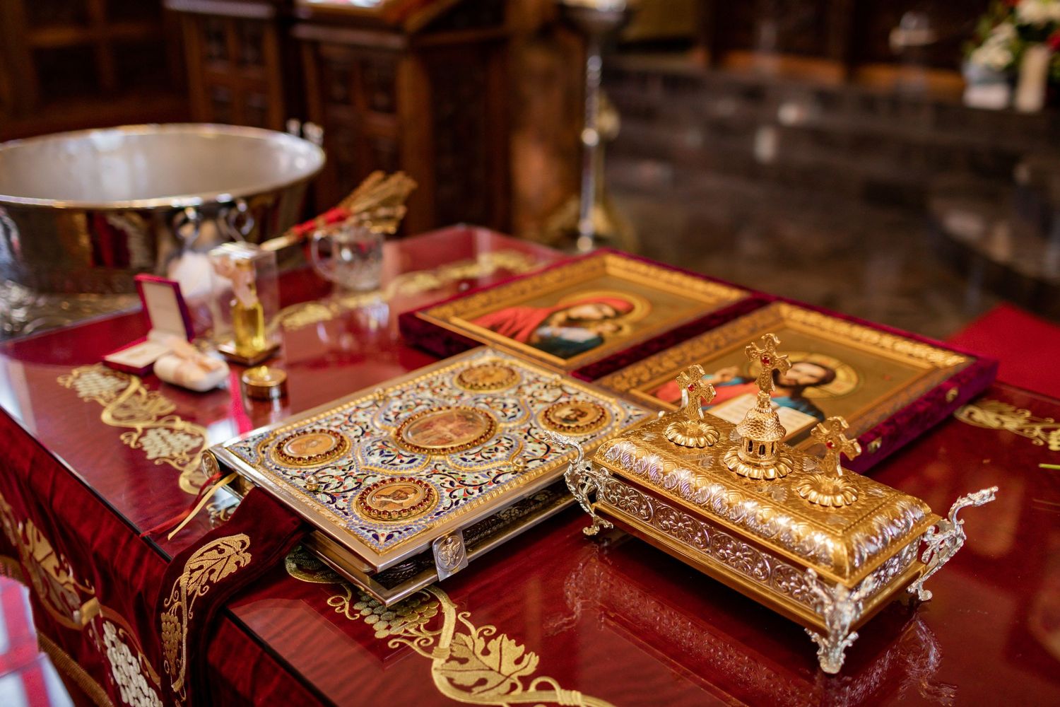 Ornate golden religious books and ceremonial items displayed on a red altar cloth.