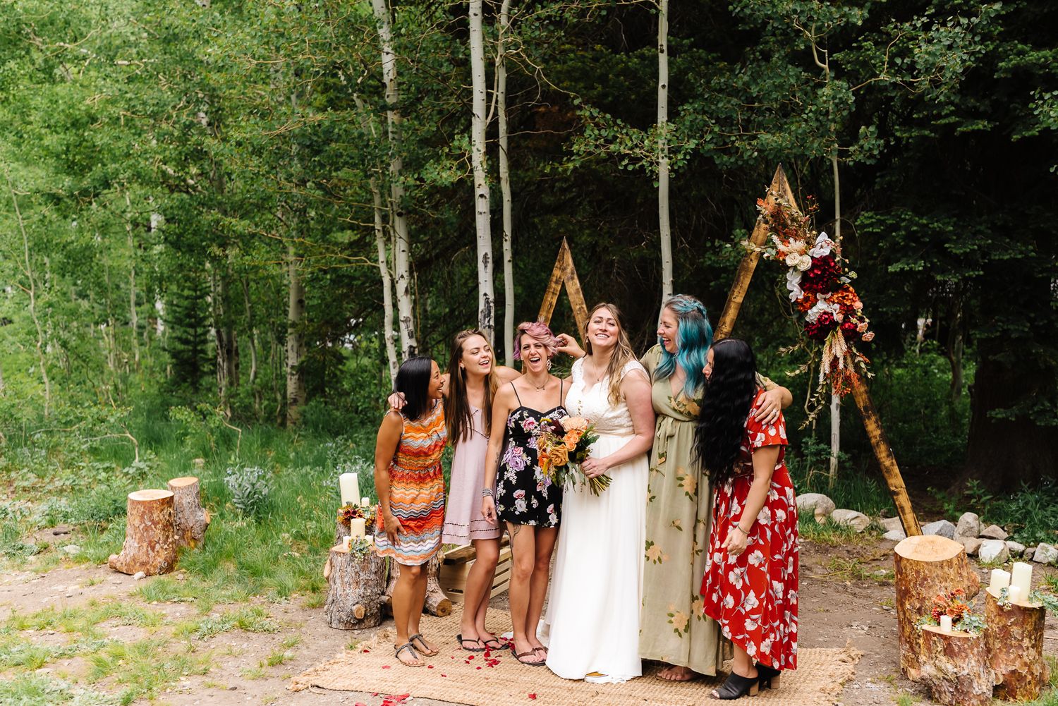 Wedding guests gather for group photos in a lush green forest setting.