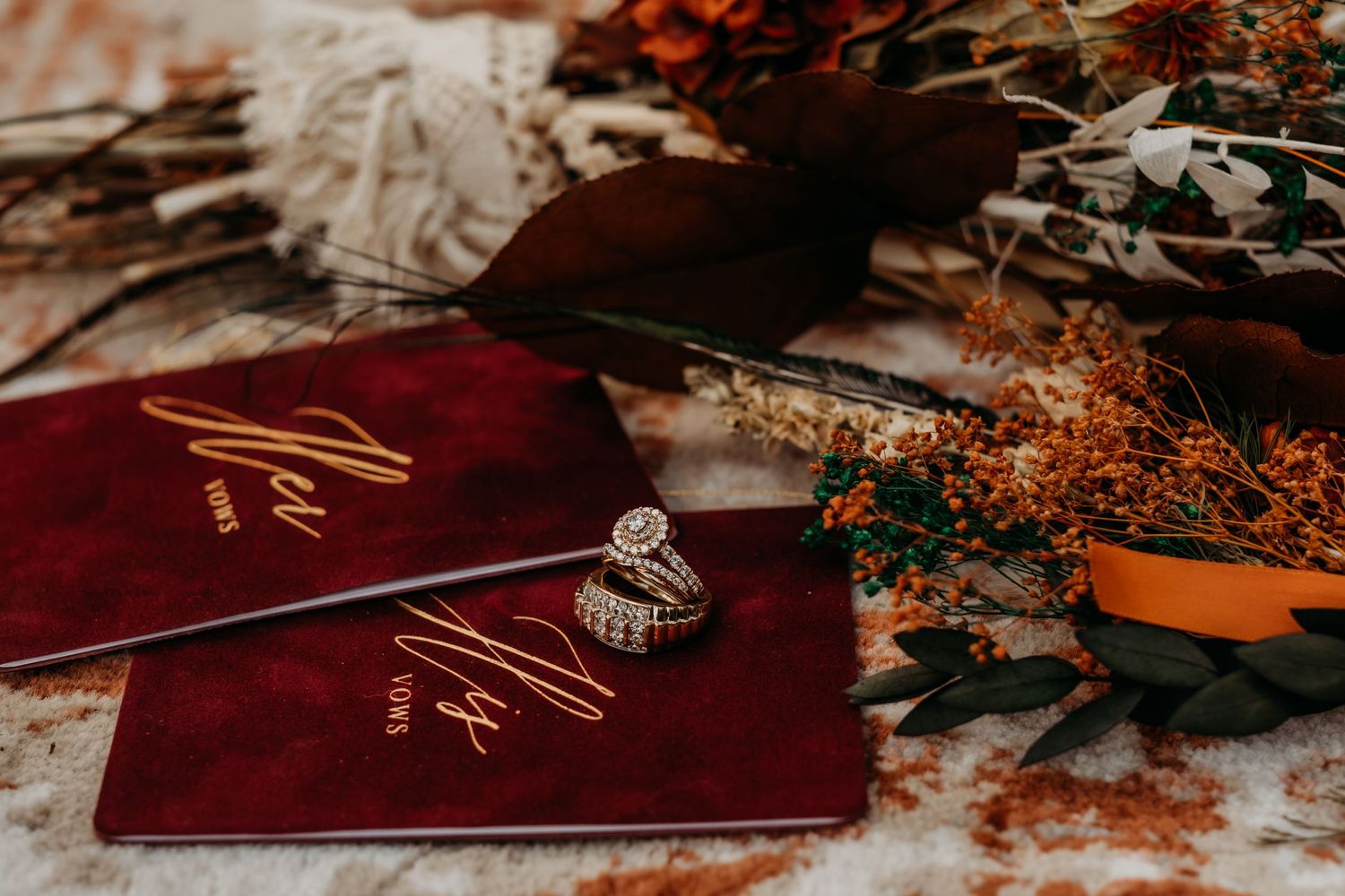 Wedding details featuring burgundy leather items and orange dried flowers arranged artistically.