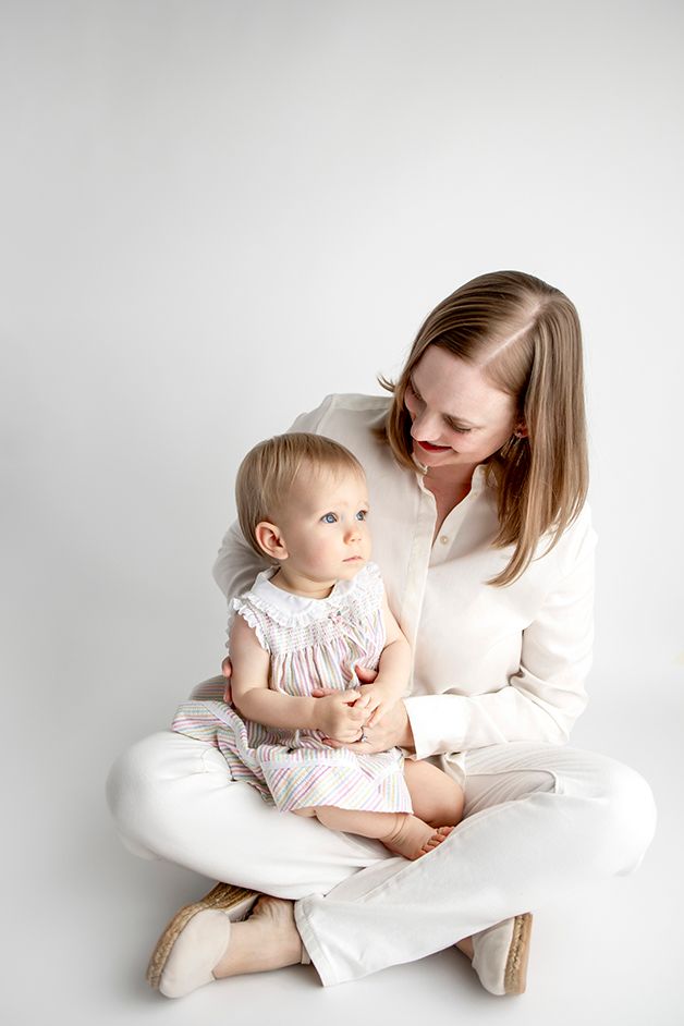 Mother sitting with daughter in her lap, gazing down at child lovingly.