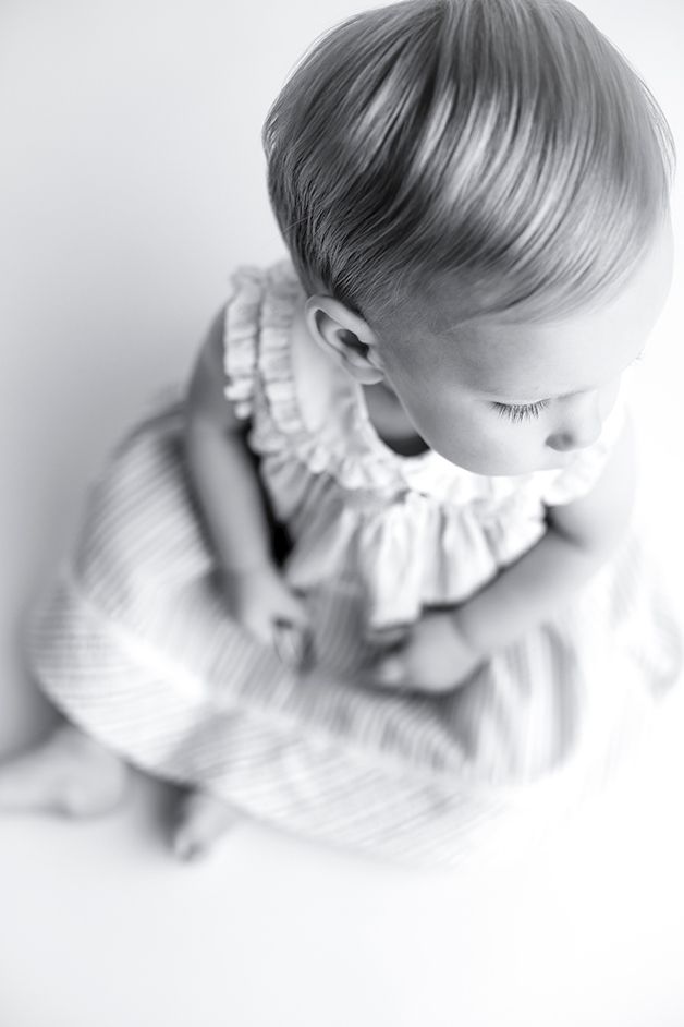 Black and white image of one year old girl shot from above, looking down.