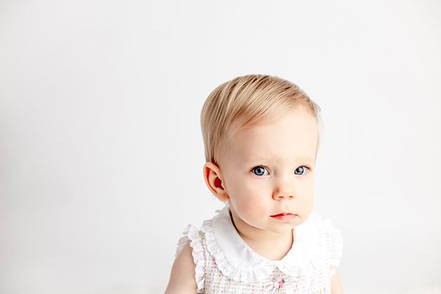 One year old girl with blond hair on white backdrop.