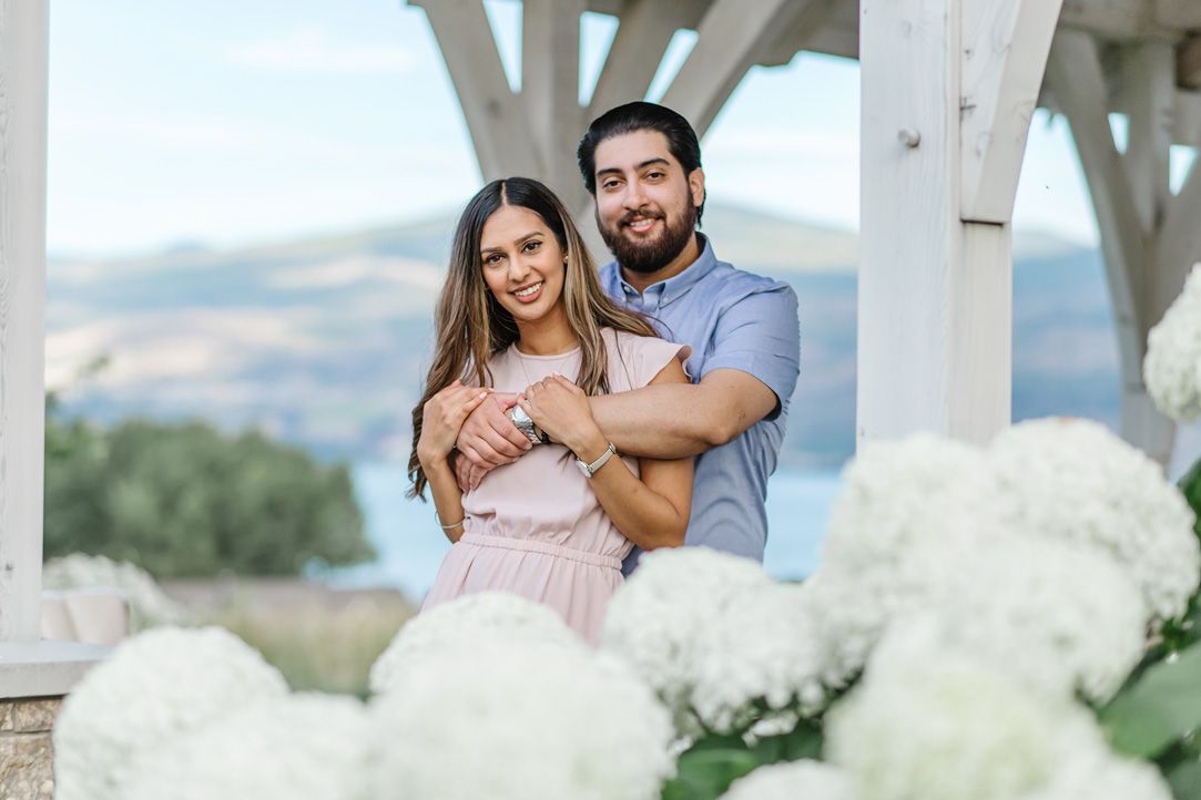 A romantic outdoor photo session with a white pergola and mountain backdrop.